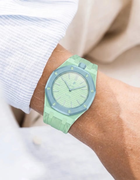 Person wearing a light green sports watch with a matching band on their wrist over a white shirt