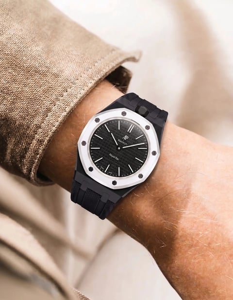 Man wearing a watch with white circular face, black dial, and black rubber strap under a beige sleeve