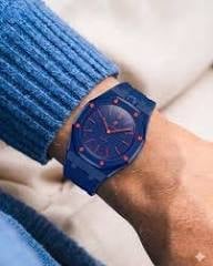 Person wearing a blue watch with brown leather strap and heart design on the dial, paired with a blue knit sweater